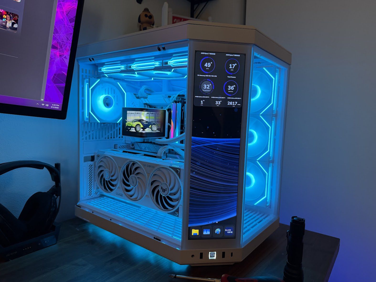 ASUS ROG Strix X870-A motherboard installed in a white-themed gaming PC build with a Ryzen 7 9800X3D, TUF GPU, and dual display panels showing system telemetry